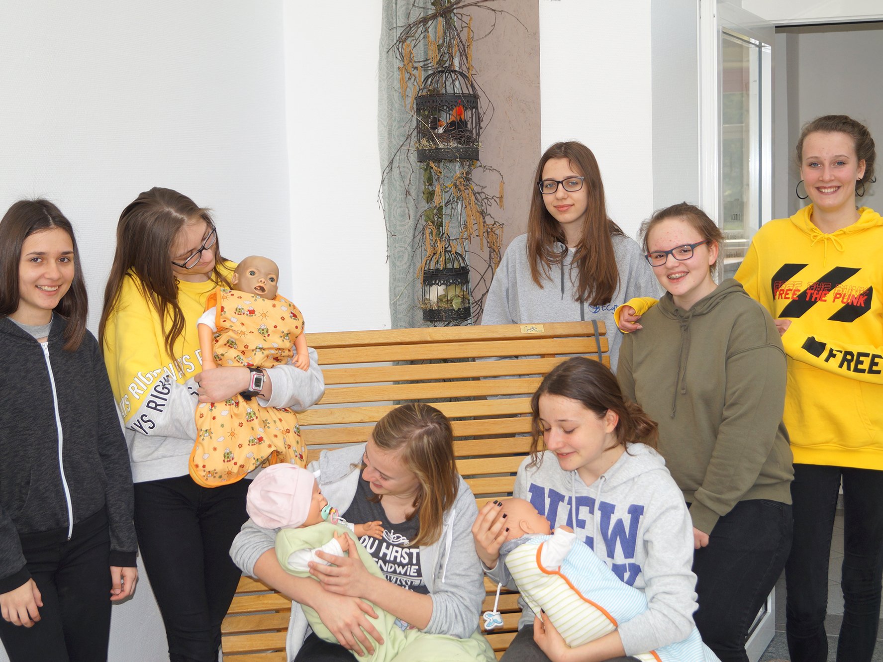 Sieben Schülerinnen halten Puppenbabies