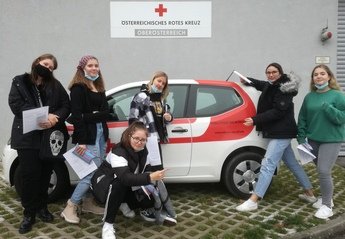 Sechs Schülerinnen stehen vor einem Auto vom Österreichischen Roten Kreuz.