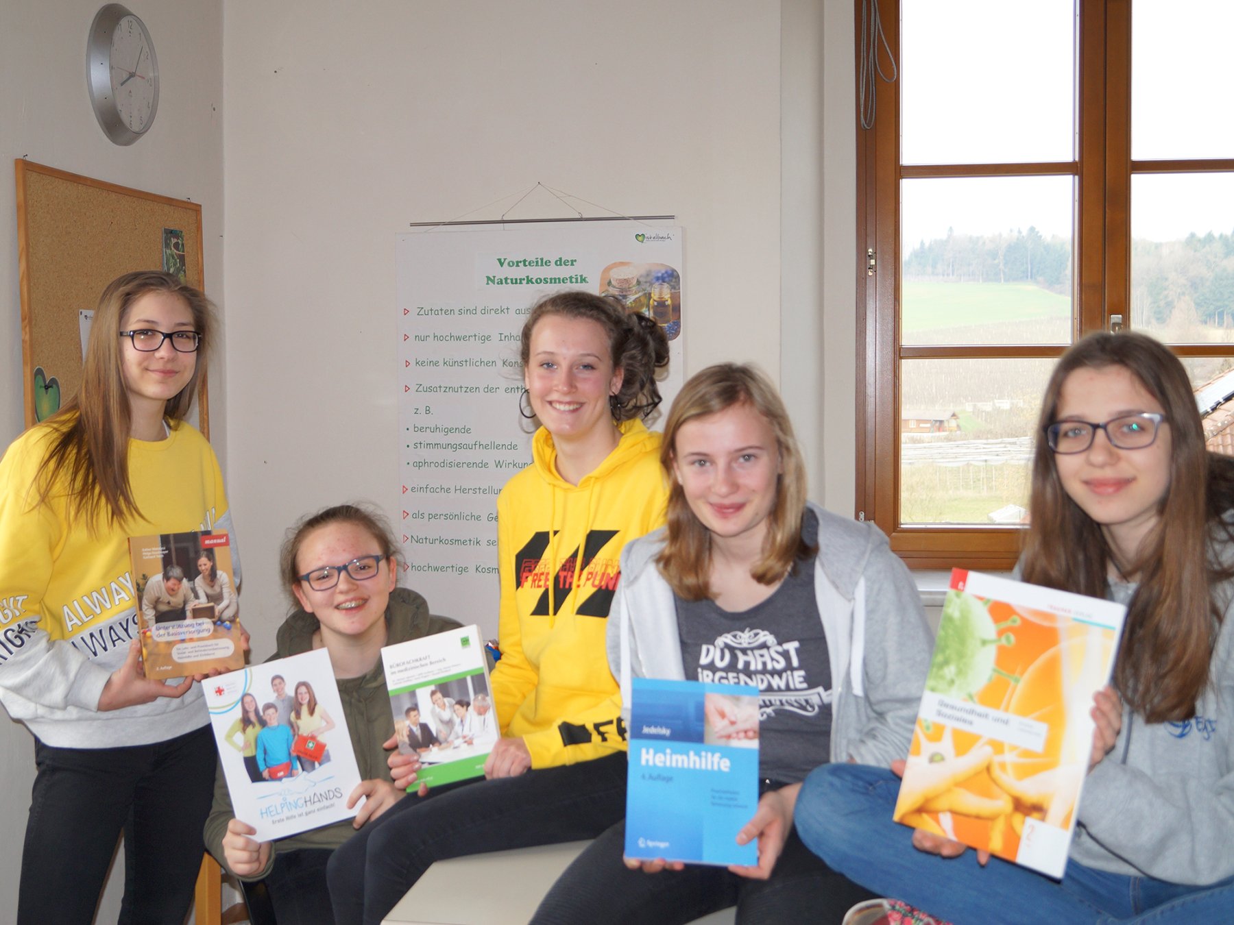 Fünf Schülerinnen zeigen Broschüren und Schulbücher